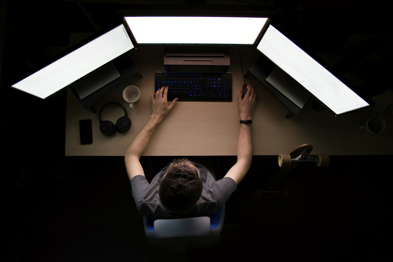 Overhead view of a multi-monitor analyst workstation in a dark room